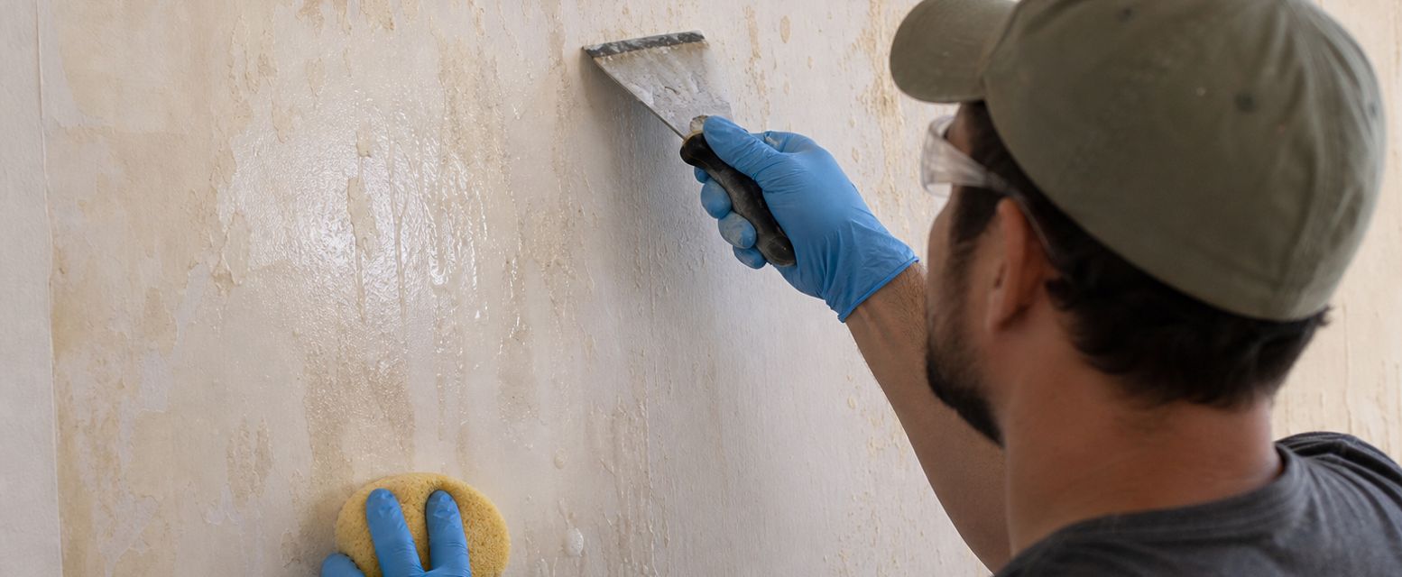Hand wiping wallpaper glue from a wall